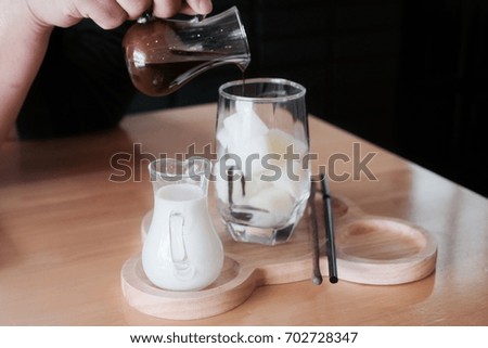 Men hand holding hot chocolate and pour into mug with milk cube. How to drink ice chocolate from cube-milk, hot milk and hot chocolate. Vintage tone.