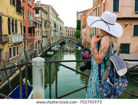 beautiful lady with a big straw hat taking a picture in Venice in Italy