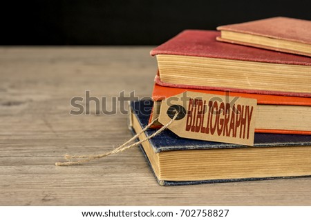 Close up of a pile of books and a kraft tag writing bibliography Royalty-Free Stock Photo #702758827