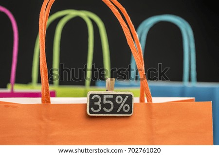 Colorful shopping bags with wooden peg tag attached writing 35 percernt discount