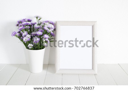 White frame with purple flower in vase on table