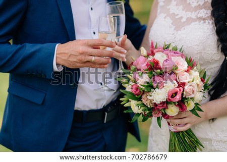 Closeup groom and bride are holding hands with a glass of champagne at wedding day and show rings. Concept of love family