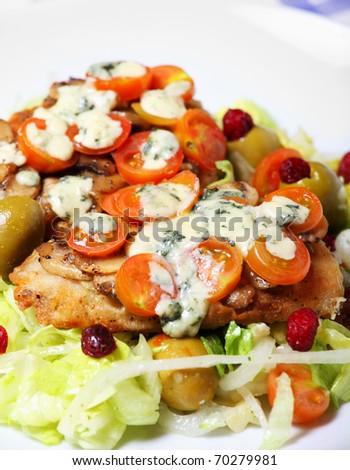 A picture of freshly baked hake fish with mushrooms, tomatoes and blue cheese on salad