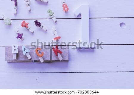 Alphabet, numbers and sign; word "back" written with painted wood letters on pink background. Top view and copy space. Baby learning concept with painted wood numers and letters.