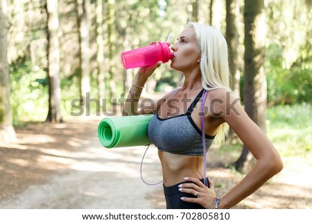 Photo of sportswoman drinking from pink bottle