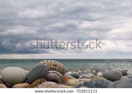 Close up of beach stones with clouds and sea on background