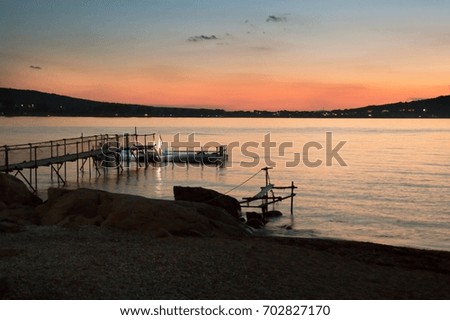 Seascape at sundown. Beautiful orange colors in the evening sky after the sunset over the silhouettes of the coastline. Romantic relax concept.