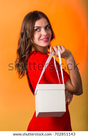 Beautiful woman in red dress holding a present box