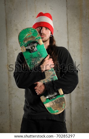 Young man holding skateboard over grunge concrete background