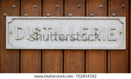 Distillerie. distillery, old stone plate on the wooden door of an old building