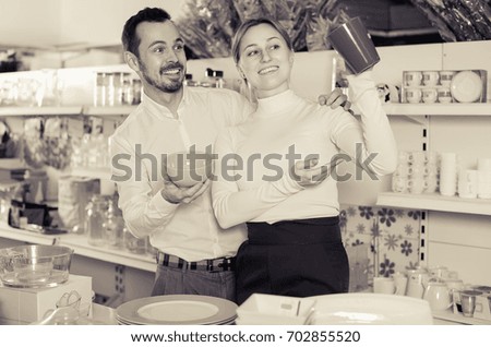 Smiling couple picks out  ceramic kitchen crockery in the store