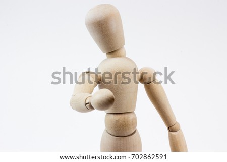 The upper body of a wooden mannequin pointing at us, in front of a white background.