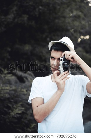 Young man with retro camera taking photos in nature