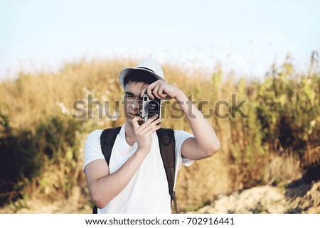 Hipster young man taking photos in nature with retro camera