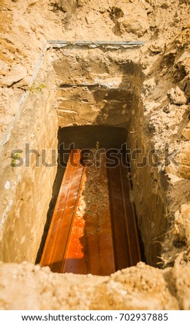 coffin is lowered into a pit