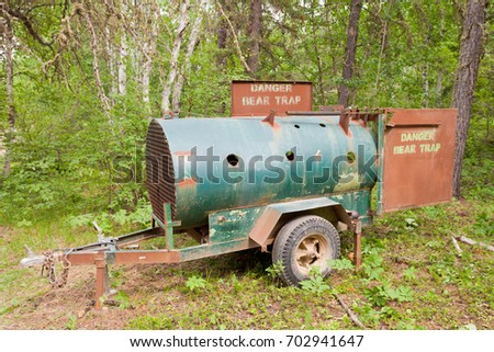 Live bear trap mobile trailer container deployed in forest wilderness to catch nuisance bear for relocation