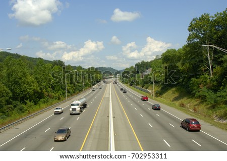 A six-lane interstate highway with divider.  Lots of travelers on a late summer day. US Highway 640 in Knoxville, Tennessee, uSA. Royalty-Free Stock Photo #702953311