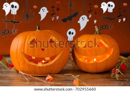 holidays, decoration and celebration concept - jack-o-lanterns or pumpkins in witch hat and halloween festive garland over dark background