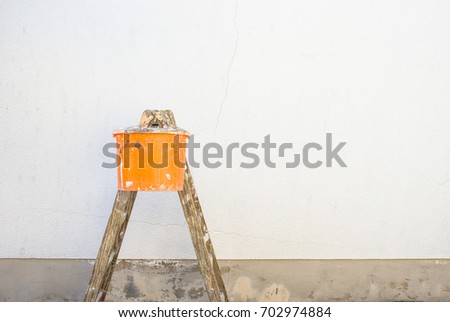House renovation, ladder and bucket in front of an empty house wall.