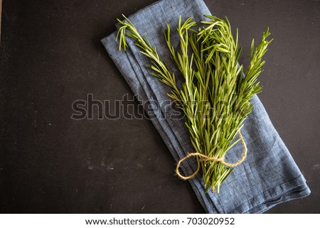 Fresh rosemary spice on dark wooden board with copyspace