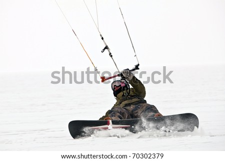 Kite surfer ride on snowboard. Snowkiting in the snow on frozen lake. Royalty-Free Stock Photo #70302379