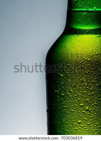 A cold green beer bottle with water drops  