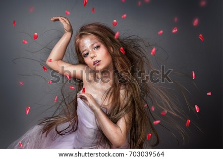 Little magical girl with flying hair with rose petals and glitters 