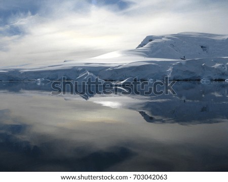 Snow and ice mountains reflecting in mirror water on a sunny day in Antarctica