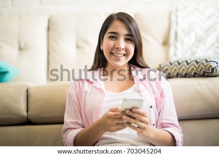 Close up portrait of a beautiful young woman using her phone for texting and smiling
