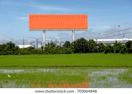 Orange billboards on green paddy field.