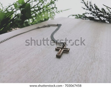 Old christian cross necklace on wood with selective focus