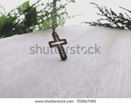 Old christian cross necklace on wooden floor with selective focus