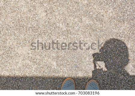 Shadow of woman that taking a photo on the floor and show her shoes with copy space on gravel texture in traveling concept
