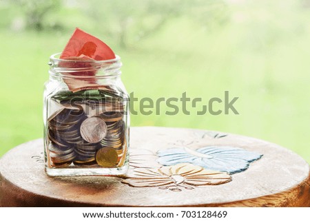 Savings for the future concept. Savings money in a glass bottle on a wooden table, soft background.