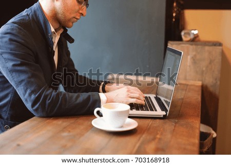 Shot of a young businessman working on his laptop in a cafe shop. Selective focus.