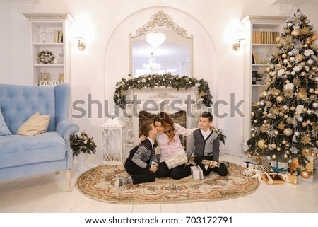 Happy mother and successful woman with children, twin boys spend time together and communicate. Guys give gifts to mother and woman presents surprise for sons from behind, family hugs and kisses in