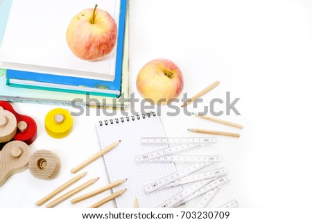 Back to school composition with white background. The items are: wooden pencils, apples, note-book, books. Top view.