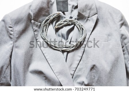 Female gray jacket and beads. Women's clothing with accessories. Flat lay stock photography, top view. Clothes for businesswoman. Style, image concept