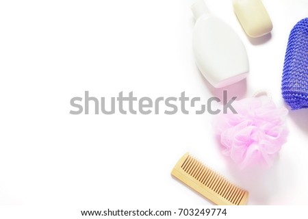 Flat lay bath products. Shampoo bottle, wooden comb, pink and purple shower sponge, baby soap on a white background. Mockup for design site, free space for text. Top view photo
