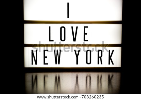 A light up board displays the phrase I LOVE NEW YORK reflected on wood