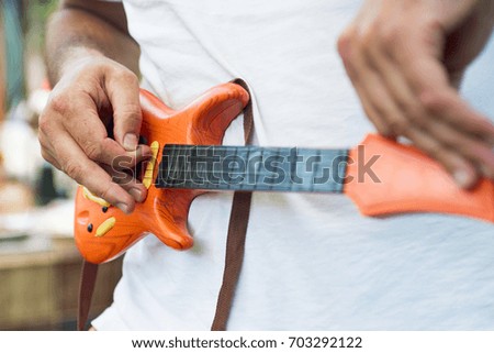 men's hands play on a toy electric guitar
