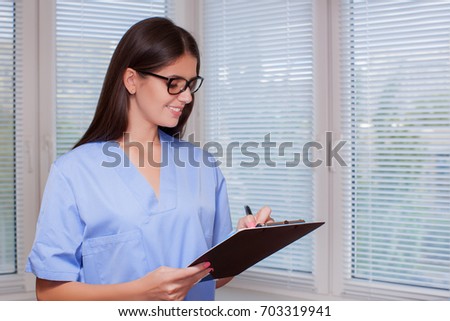 Close-up India medicine physician in blue clothes, friendly woman in glasses looking at appointment or medical history      