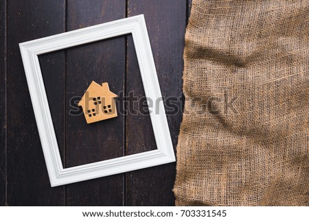 Symbol home within white frame and hemp sack on wooden floor