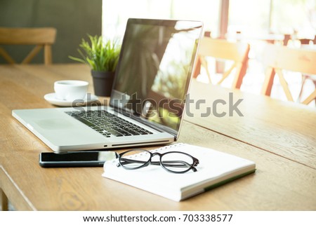 Business equipment laptop with cell phone and eyeglasses on wooden desk