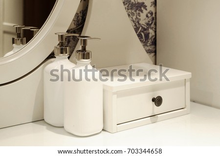 close up white bottle glass and drawer on white dresser mirror in bedroom