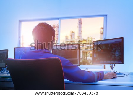 Professional technician sitting in control room monitoring process petrochemical plant, Asian broad man operate process plant, Engineers work Royalty-Free Stock Photo #703450378