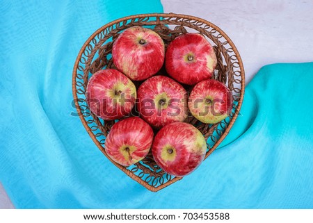 Big beautiful red delicious apples in a wicker plate on a turquoise blue background