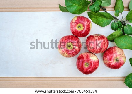 Beautiful picture with great red apples and a branch with green leaves on a light background with copy space