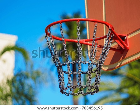 A close up of a basketball hoop with some palm trees on a blurred background.
