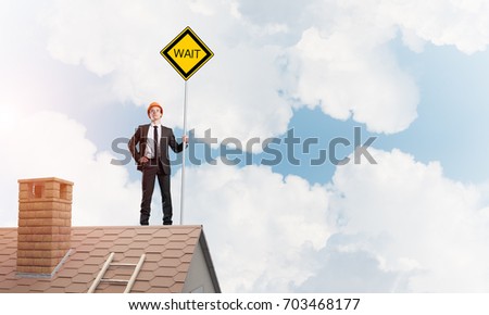 Man in suit and helmet holding yellow sign on stick. Mixed media